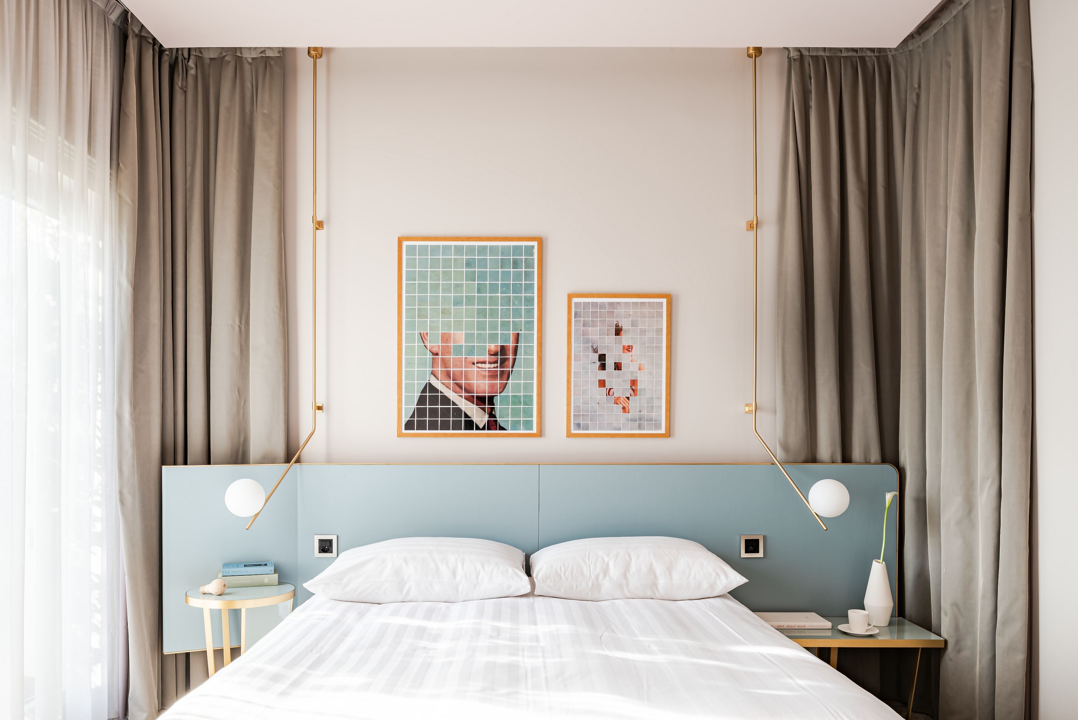 A hotel room with a bed, bedside tables, a nightstand, a lamp, and two framed pictures on the wall.