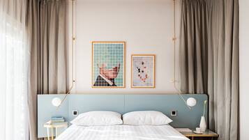 A hotel room with a bed, bedside tables, a nightstand, a lamp, and two framed pictures on the wall.
