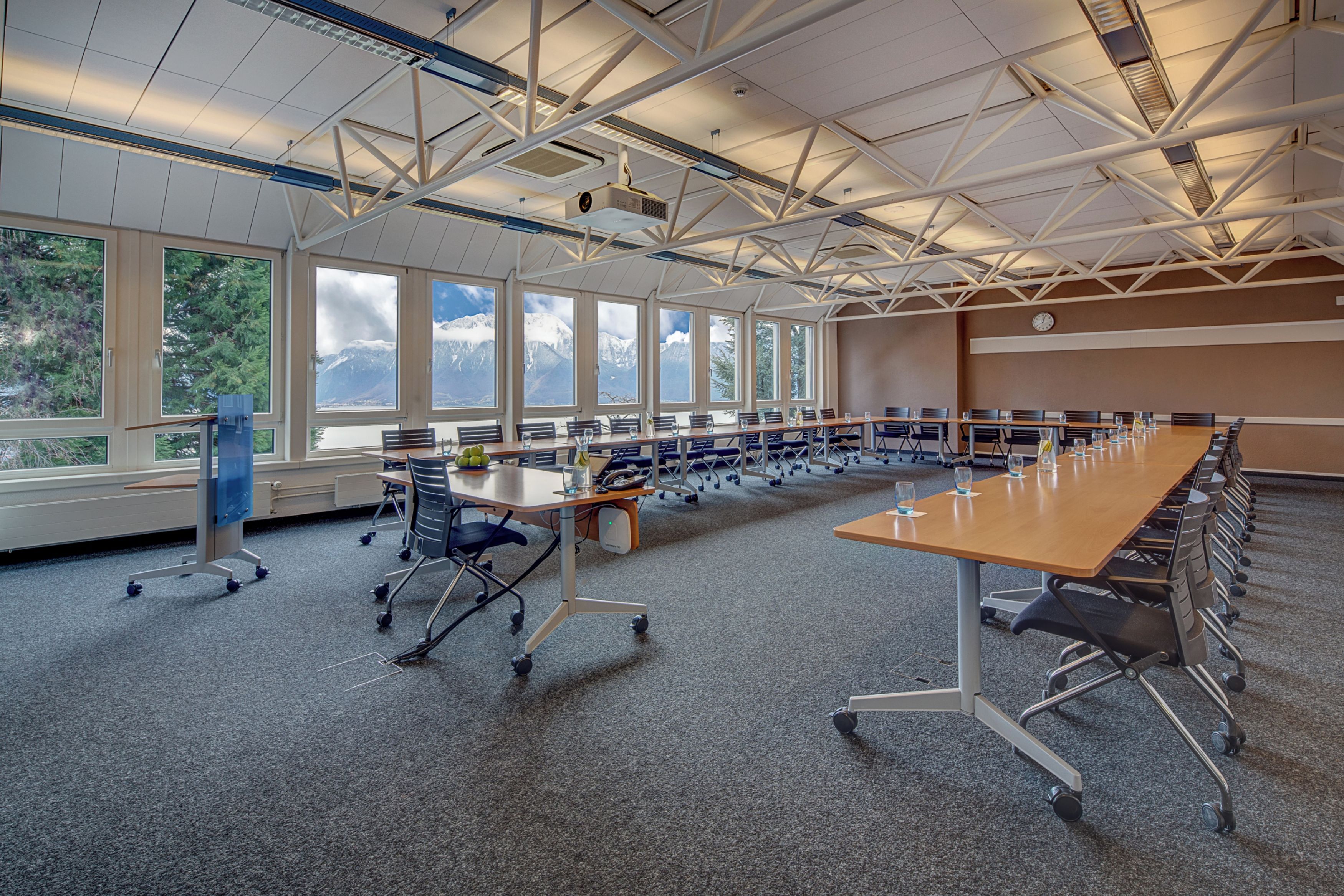 Uma sala de conferências com uma mesa comprida, cadeiras e amplas janelas com vista para as montanhas.