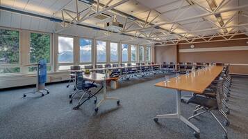 Uma sala de conferências com uma mesa comprida, cadeiras e amplas janelas com vista para as montanhas.