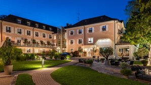 A hotel with a courtyard, outdoor seating, and a well-lit entrance. - Hotel du Leman (Jongny)