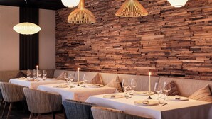 A dining area with a long table set for six, wooden wall paneling, and pendant lighting. - Hotel Ambassador Zermatt (Zermatt)