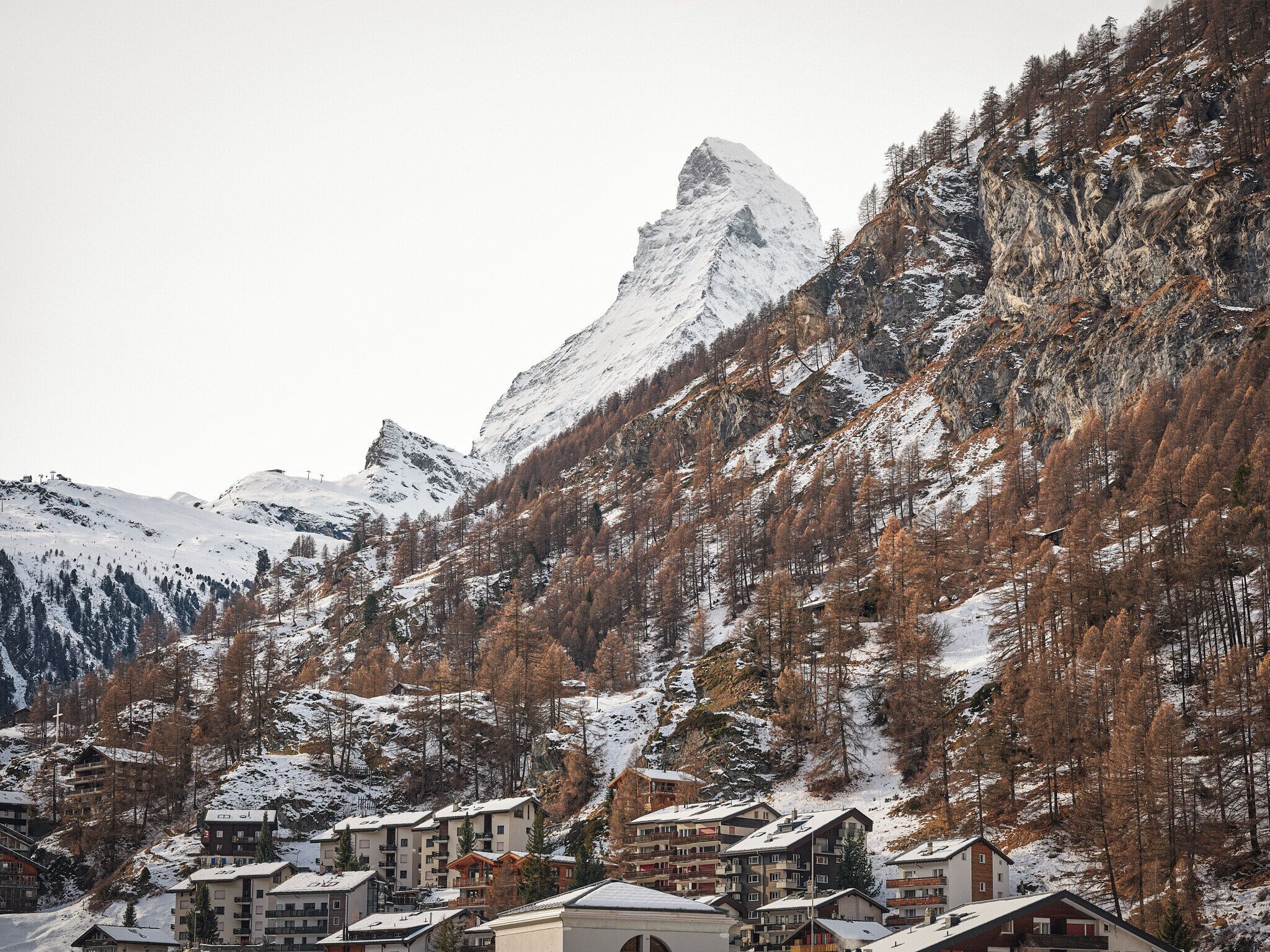 A mountain resort with snow-covered buildings and a prominent peak in the background.