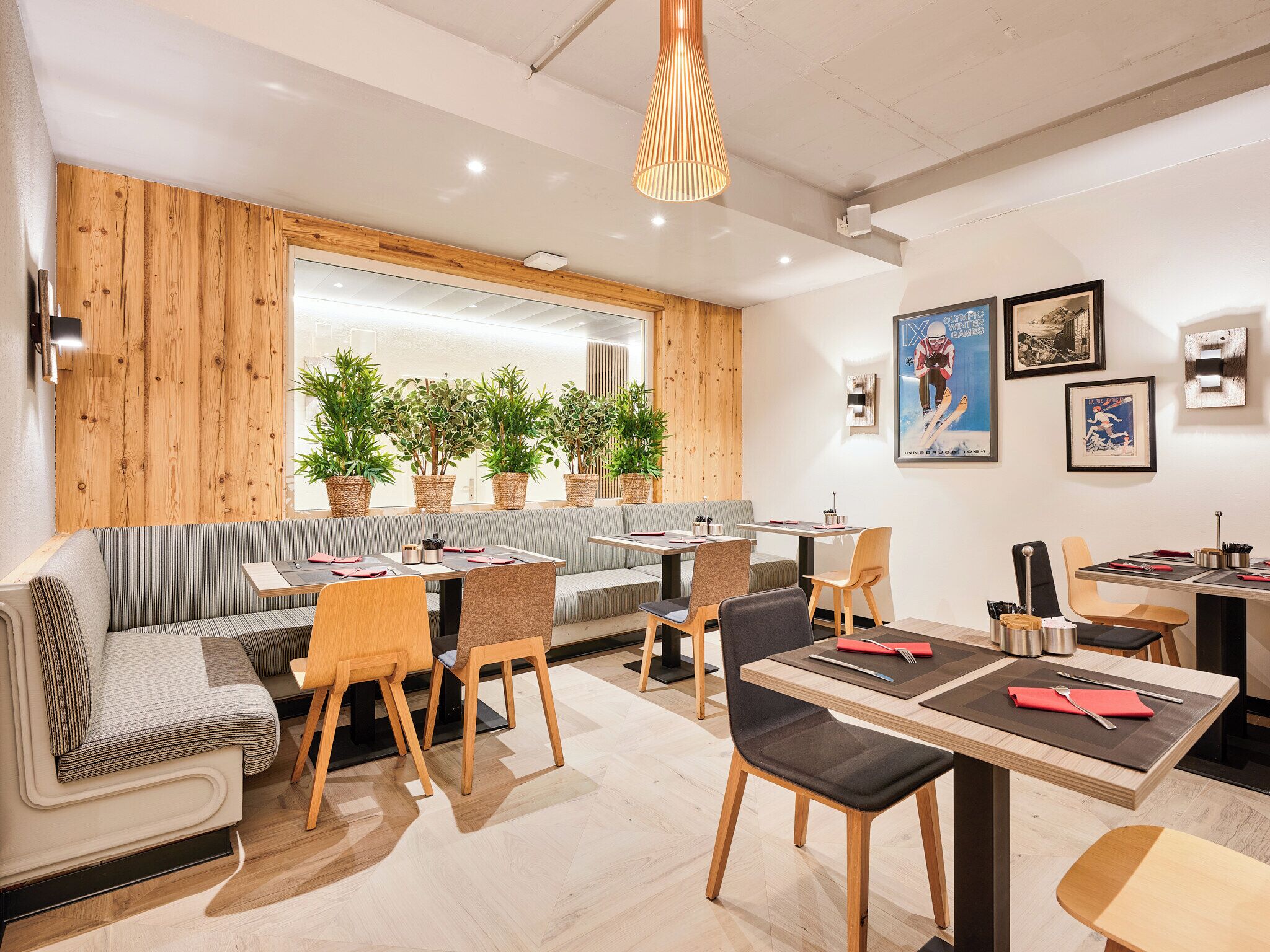 A modern dining area with wooden accents, striped seating, and potted plants.