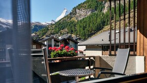 A balcony with a view of a mountain, a table, and chairs. - Hotel Ambassador Zermatt (Zermatt)