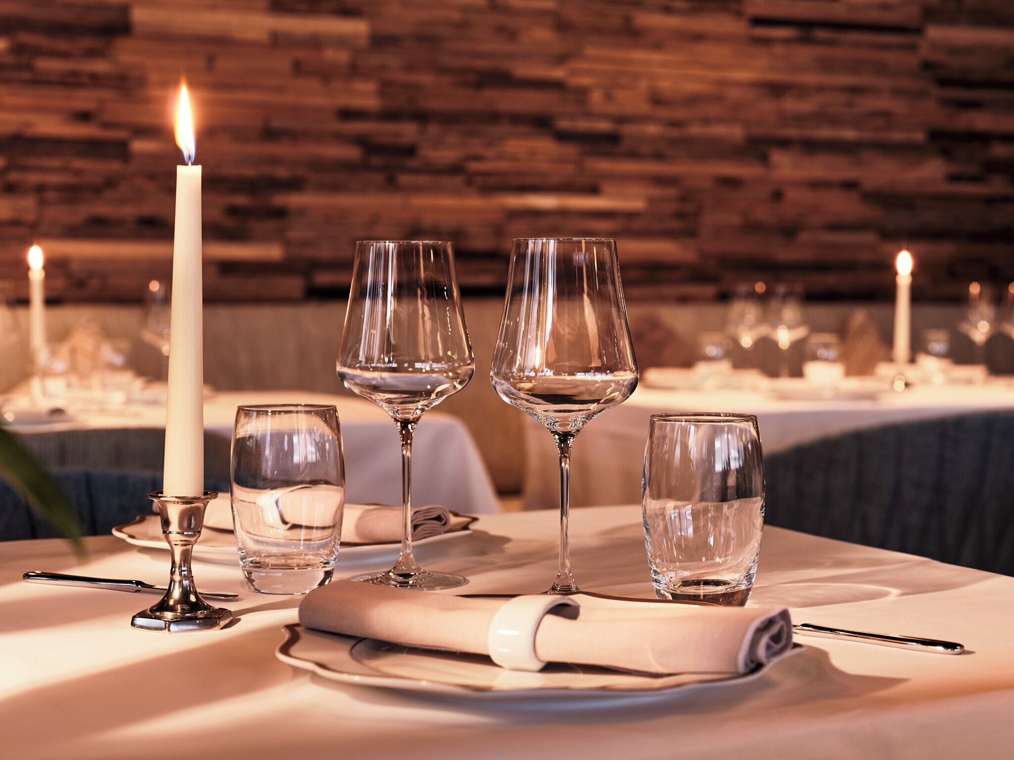 A table set for dining with wine glasses, a candle, and a folded napkin.