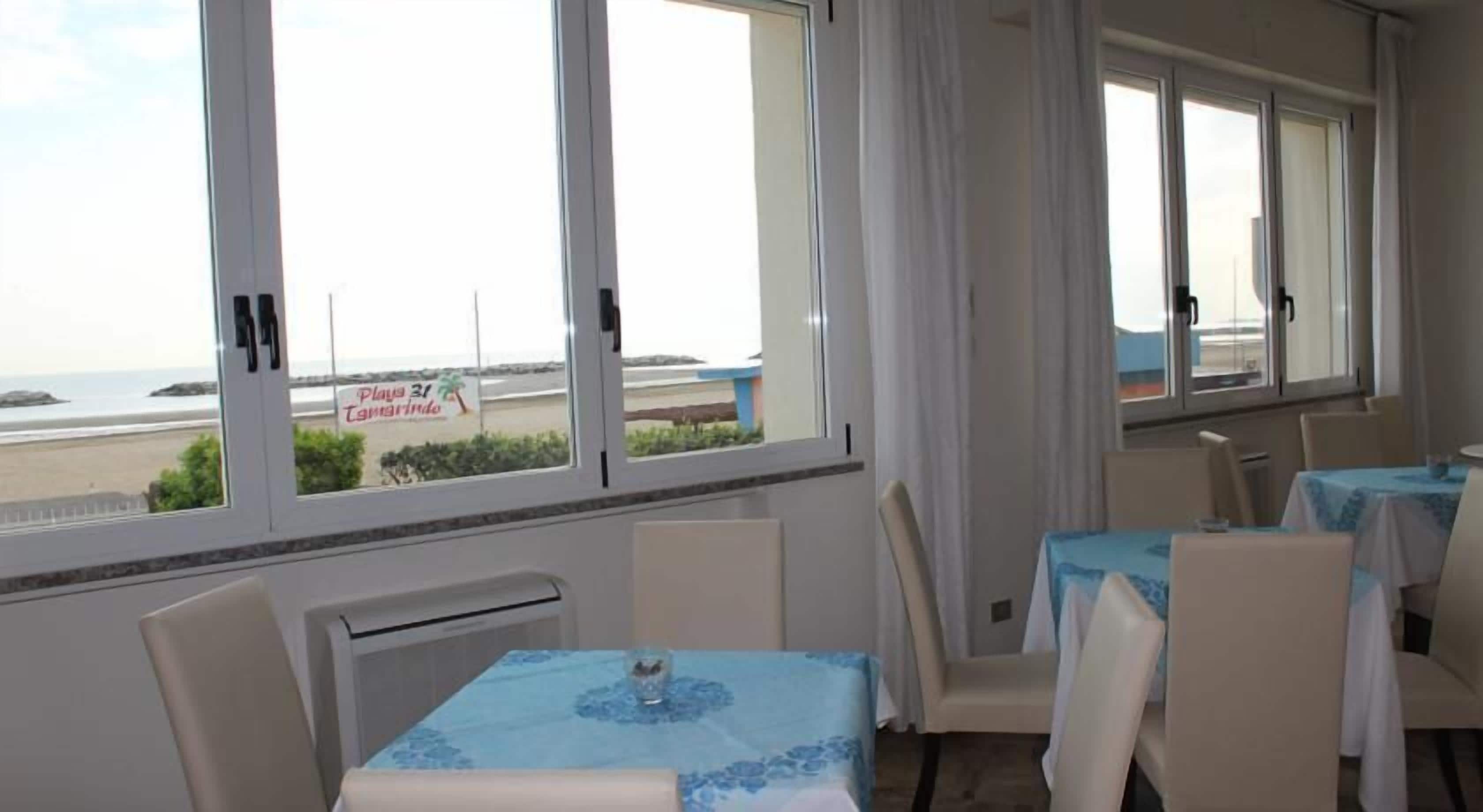 Una habitación de hotel con vista a la playa, un comedor con mesas y sillas, y un letrero que indica Playa 31 Tamarindo.