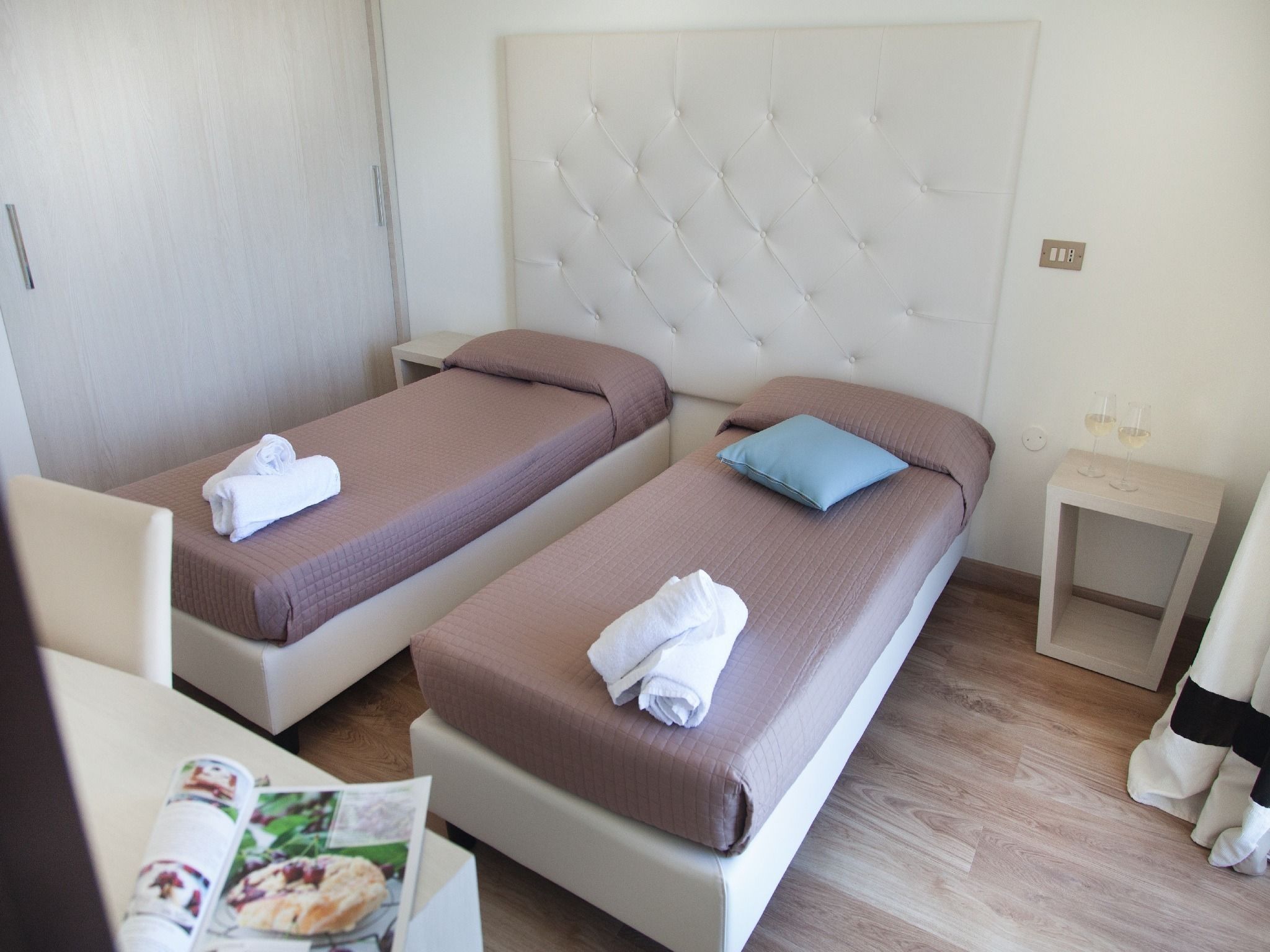Ein Hotelzimmer mit zwei Einzelbetten, einem kleinen Nachttisch und einem Sessel.