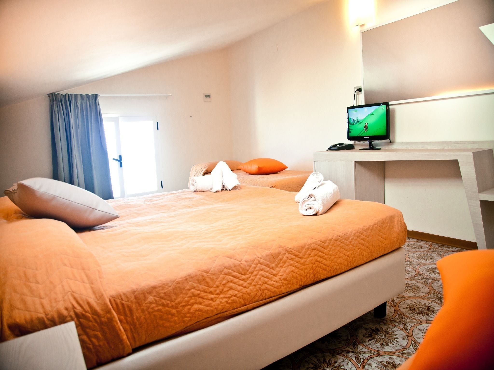 Una habitación de hotel con una cama, un escritorio y una televisión.