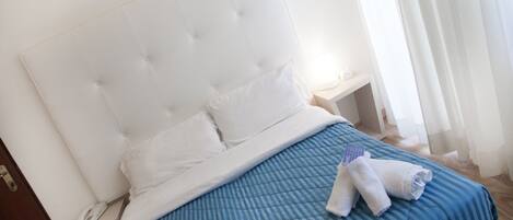 A neatly made bed with a blue quilt, white pillows, and a white headboard.