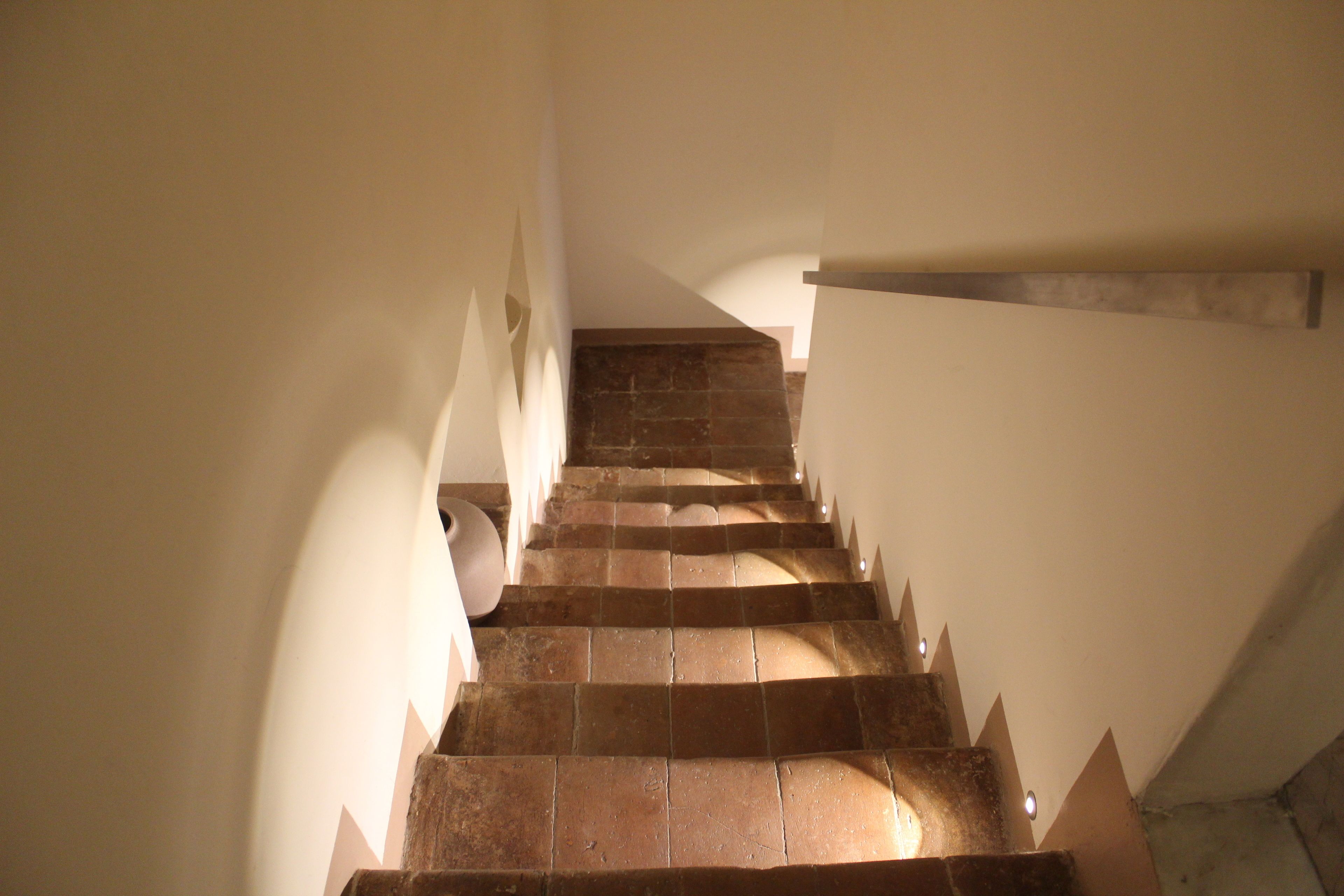 A staircase with stone steps and a handrail, leading upwards.