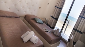 A hotel room with two beds, a large window with curtains, and a view of the beach. - Riviera Mare Beach Life Hotel (Rimini)