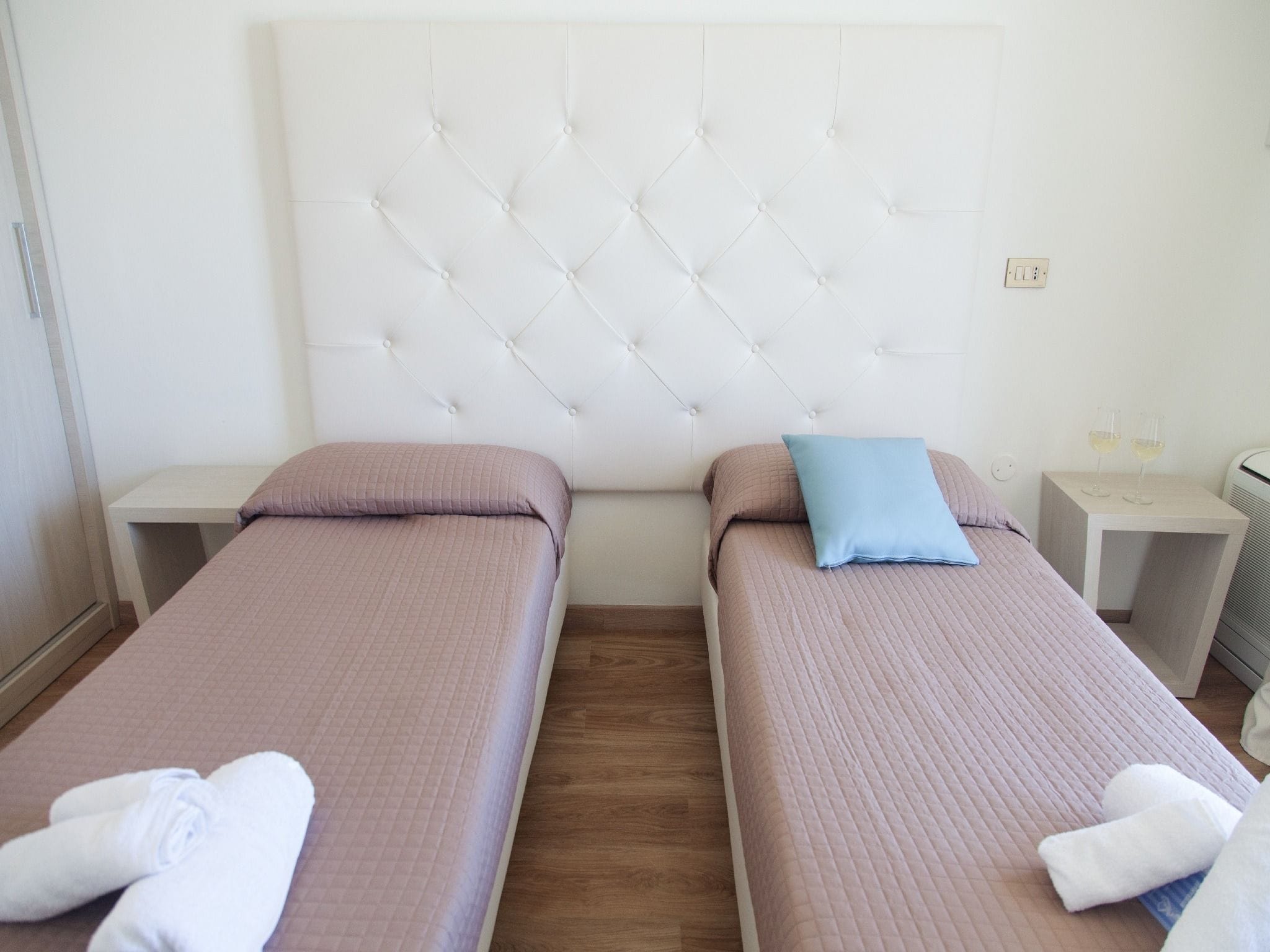 Une chambre d’hôtel avec deux lits simples, chacun doté d’une tête de lit, d’une table de chevet et d’une petite table de nuit.