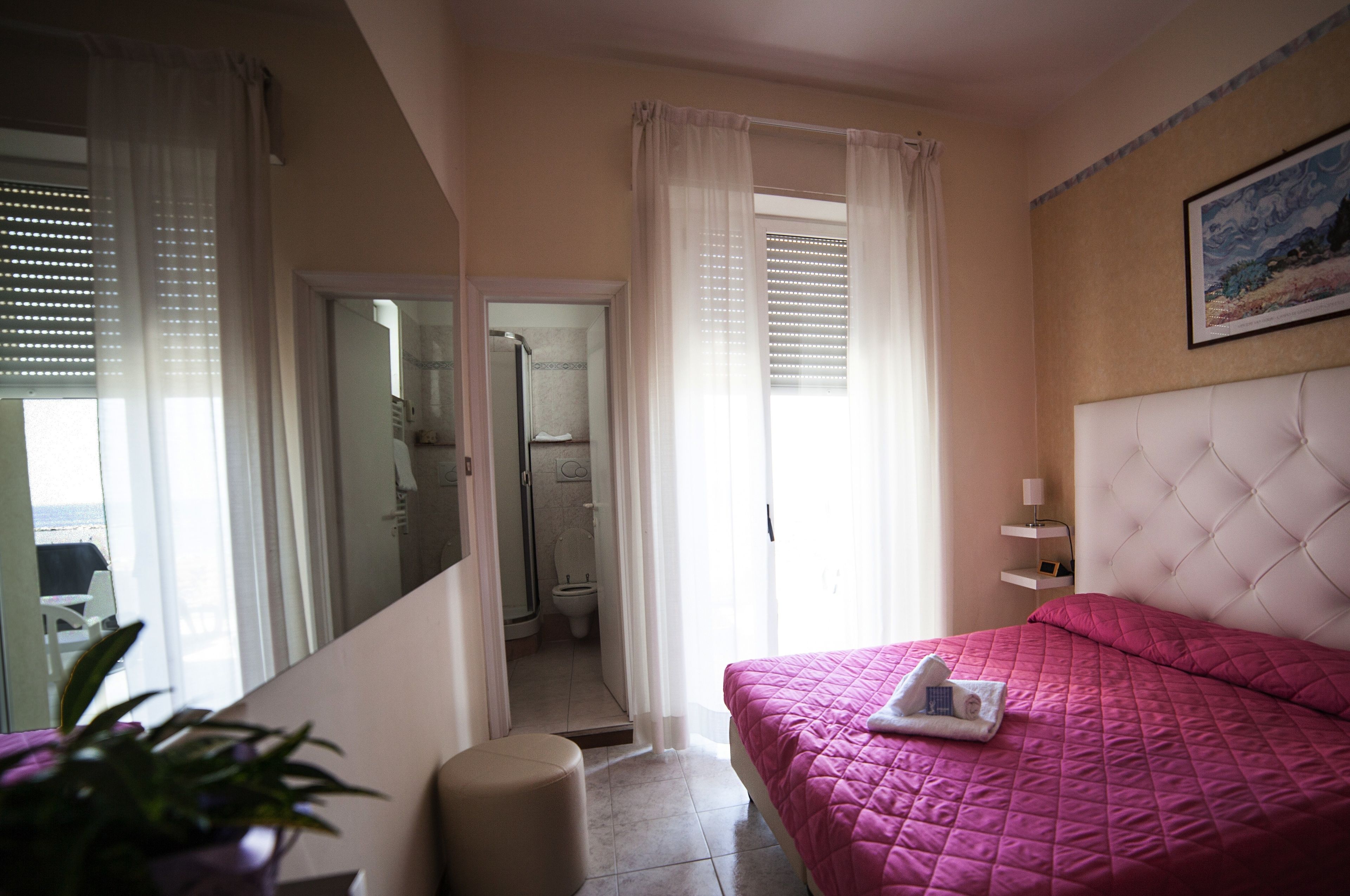A hotel room with a bed, a bathroom, and a view of the sea.