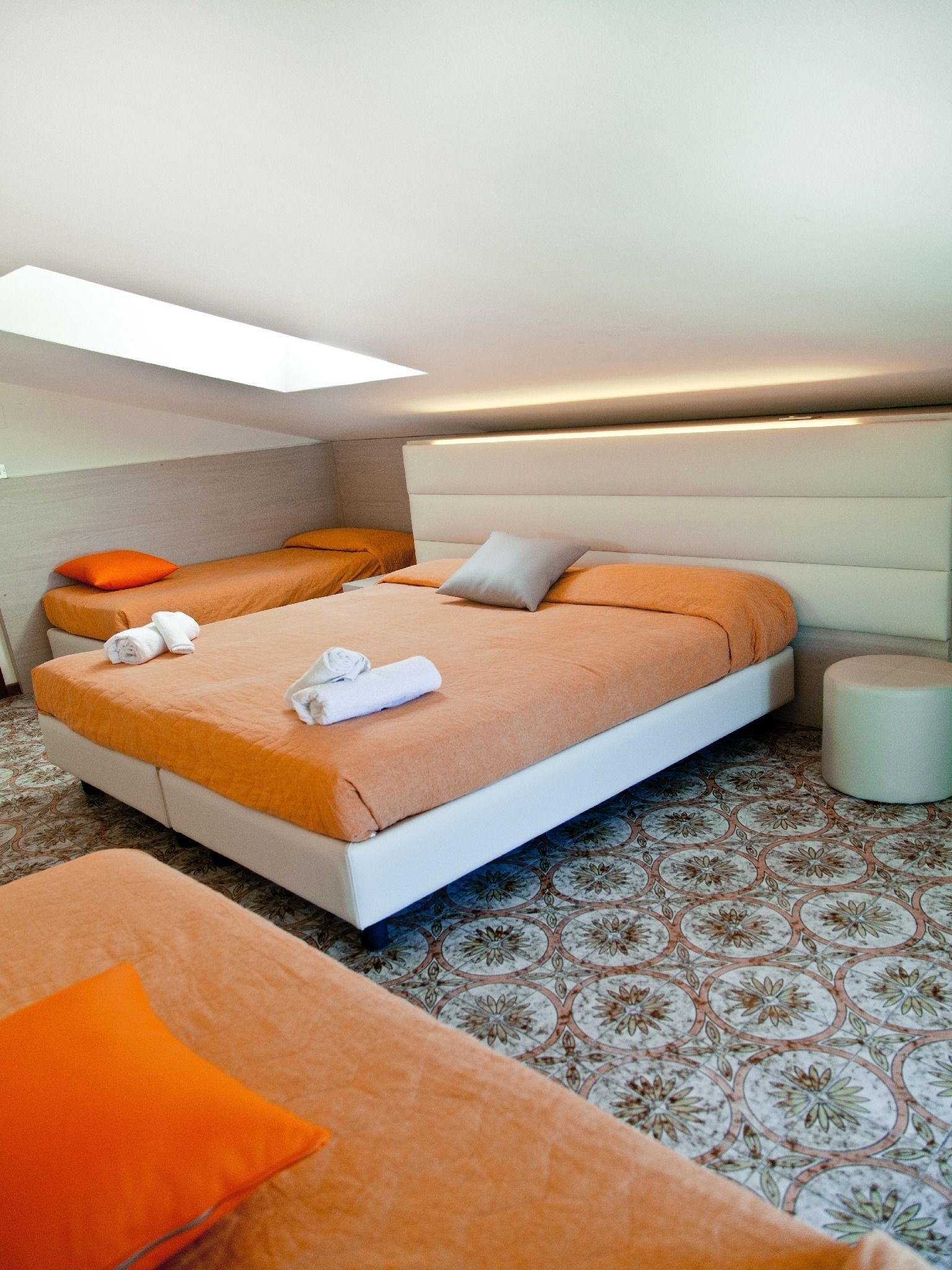 A modern hotel room with a large bed, a smaller bed, and a seating area.