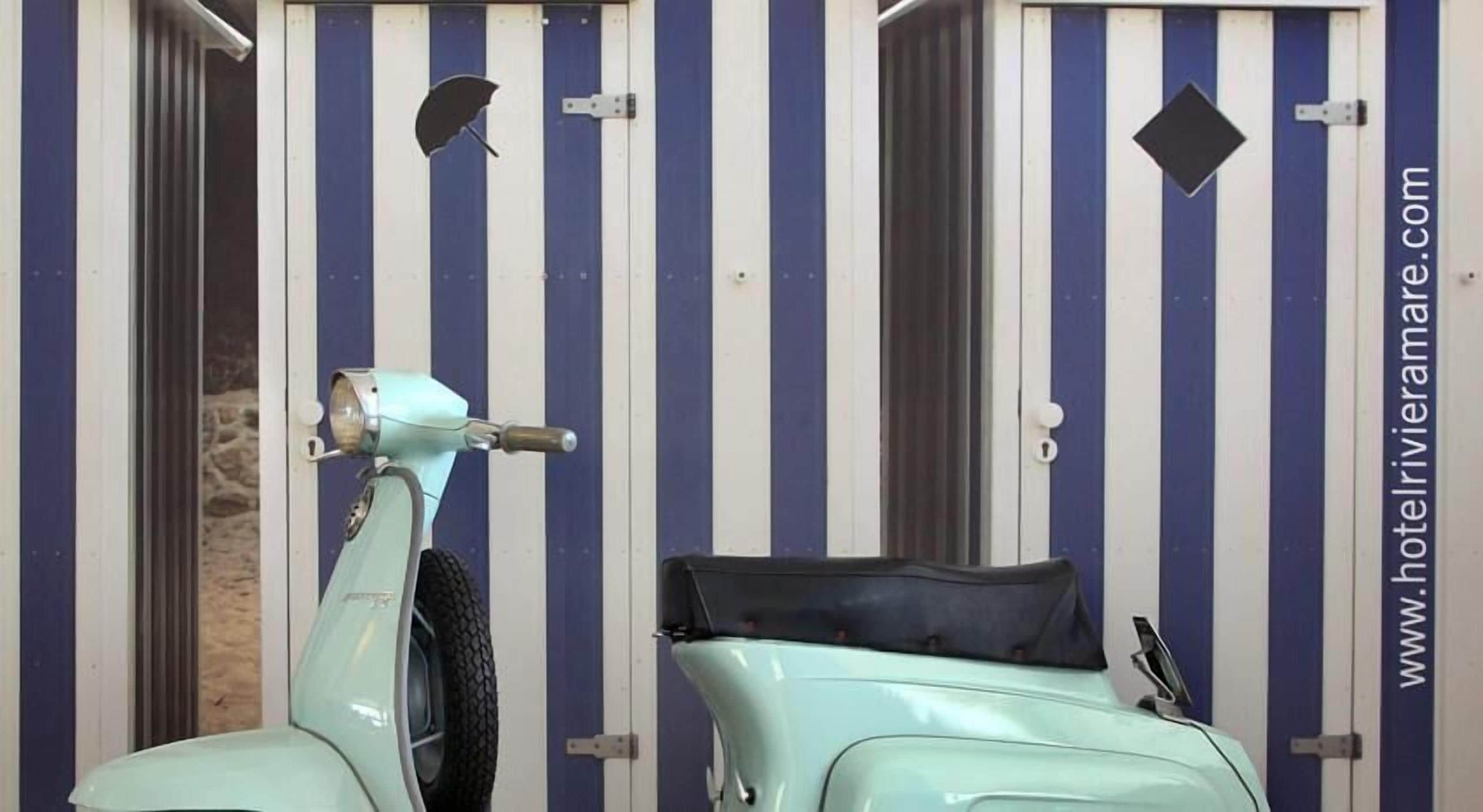 A vintage scooter parked in front of a striped door with a website URL visible.