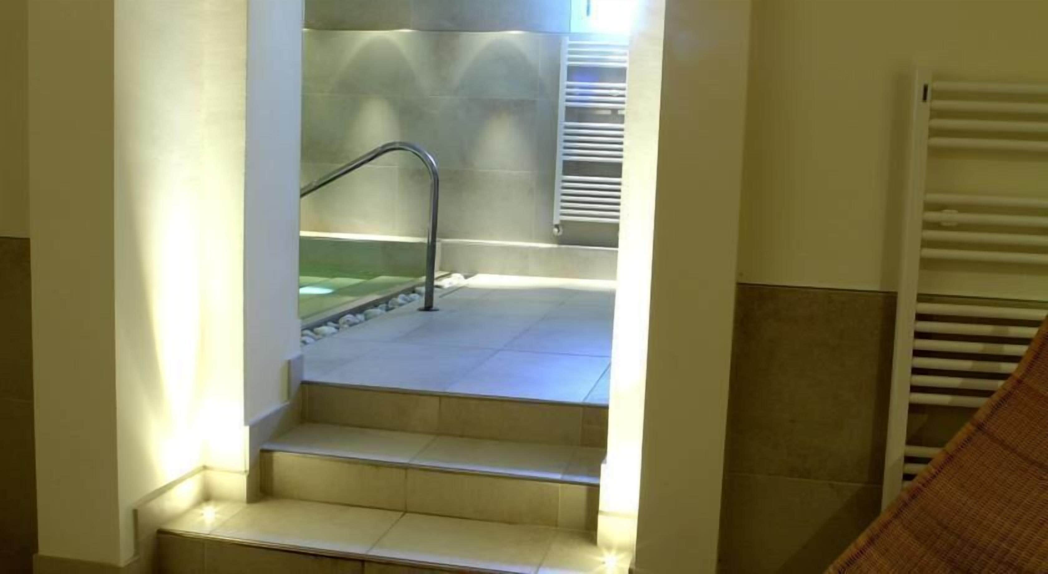 Escadaria que leva a uma varanda com guarda-corpo de metal e vista para uma área de piscina.