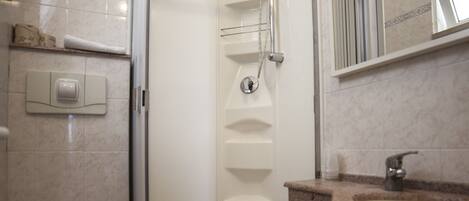 Un baño con ducha, inodoro, bidé y lavamanos.