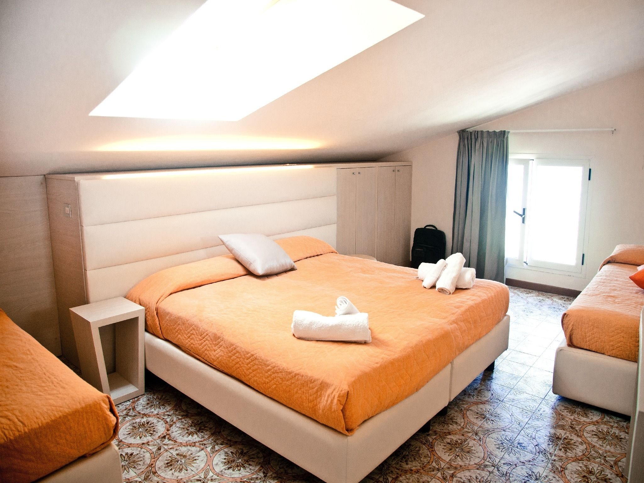 A hotel room with a large bed, a bedside table, a wardrobe, and a window with curtains.