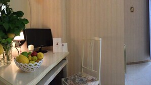 Une chambre d’hôtel avec un lit, une table de chevet sur laquelle se trouve une bouteille de champagne, une chaise, une petite table avec des assiettes de nourriture et une plante.