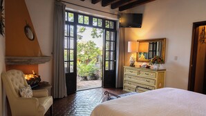 Un dormitorio con cama, una silla, cómoda, espejo y chimenea.