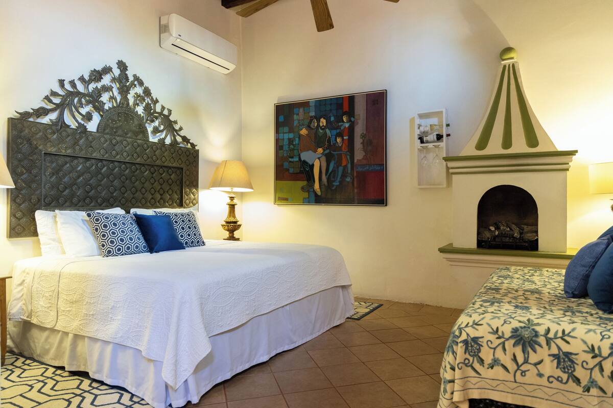 Ein Schlafzimmer mit Bett, Kamin und einem an der Wand befestigten Kunstwerk.
