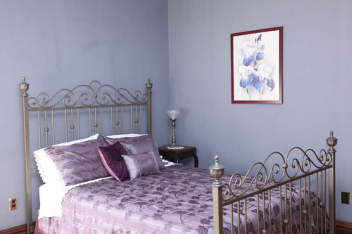A bedroom with a bed, a nightstand, and a framed picture on the wall.