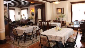 Un espace repas comprenant une grande table et des chaises, un plancher en bois et un lustre.