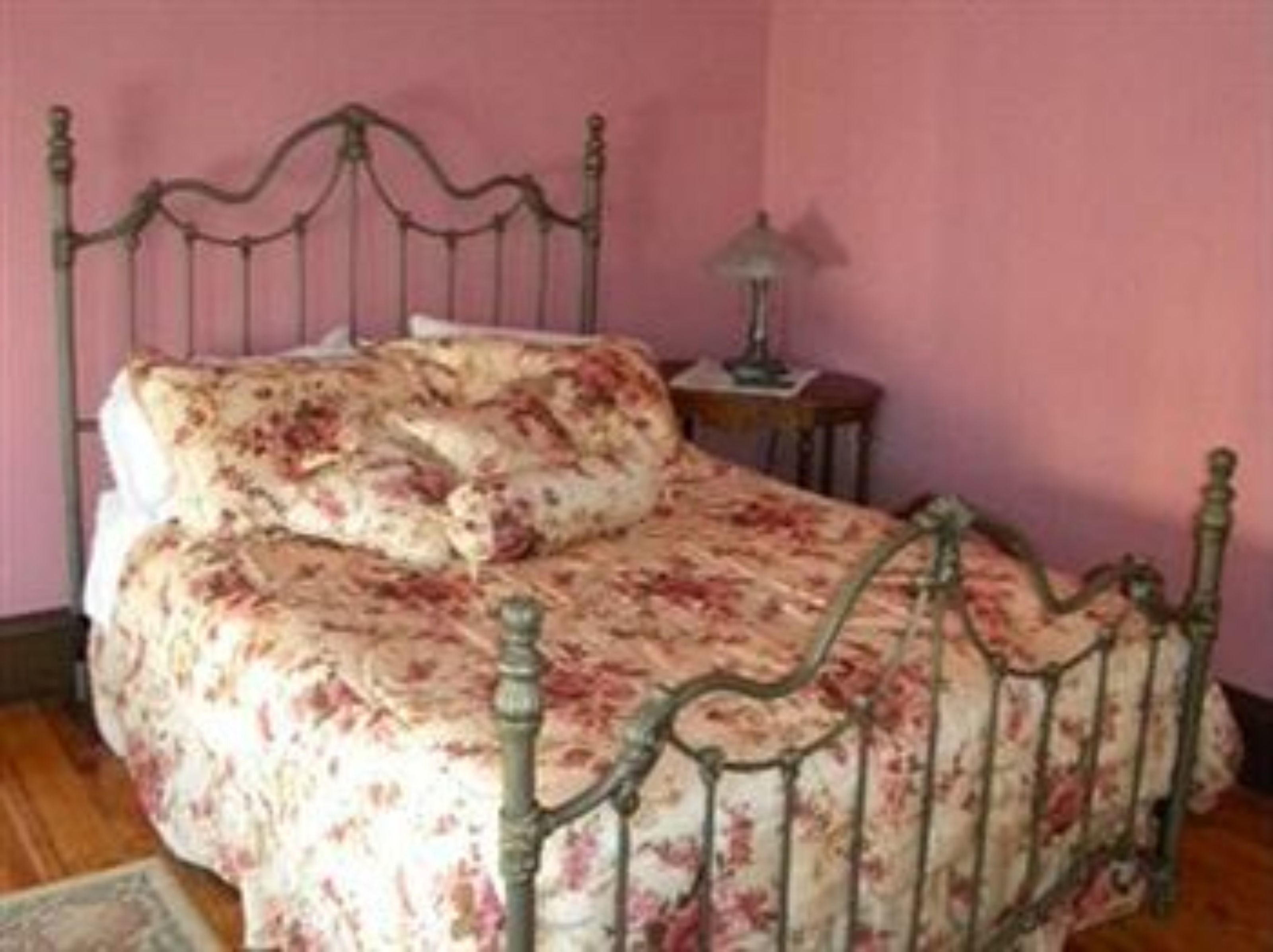 A bed with a floral bedspread and a metal frame.