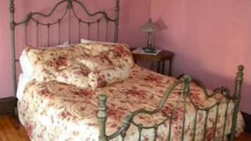 A bed with a floral bedspread and a metal frame.
