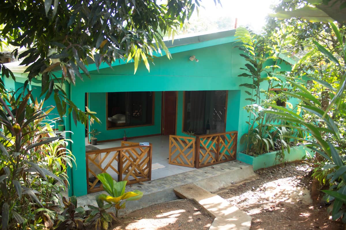 A turquoise building with large windows and a covered patio area.