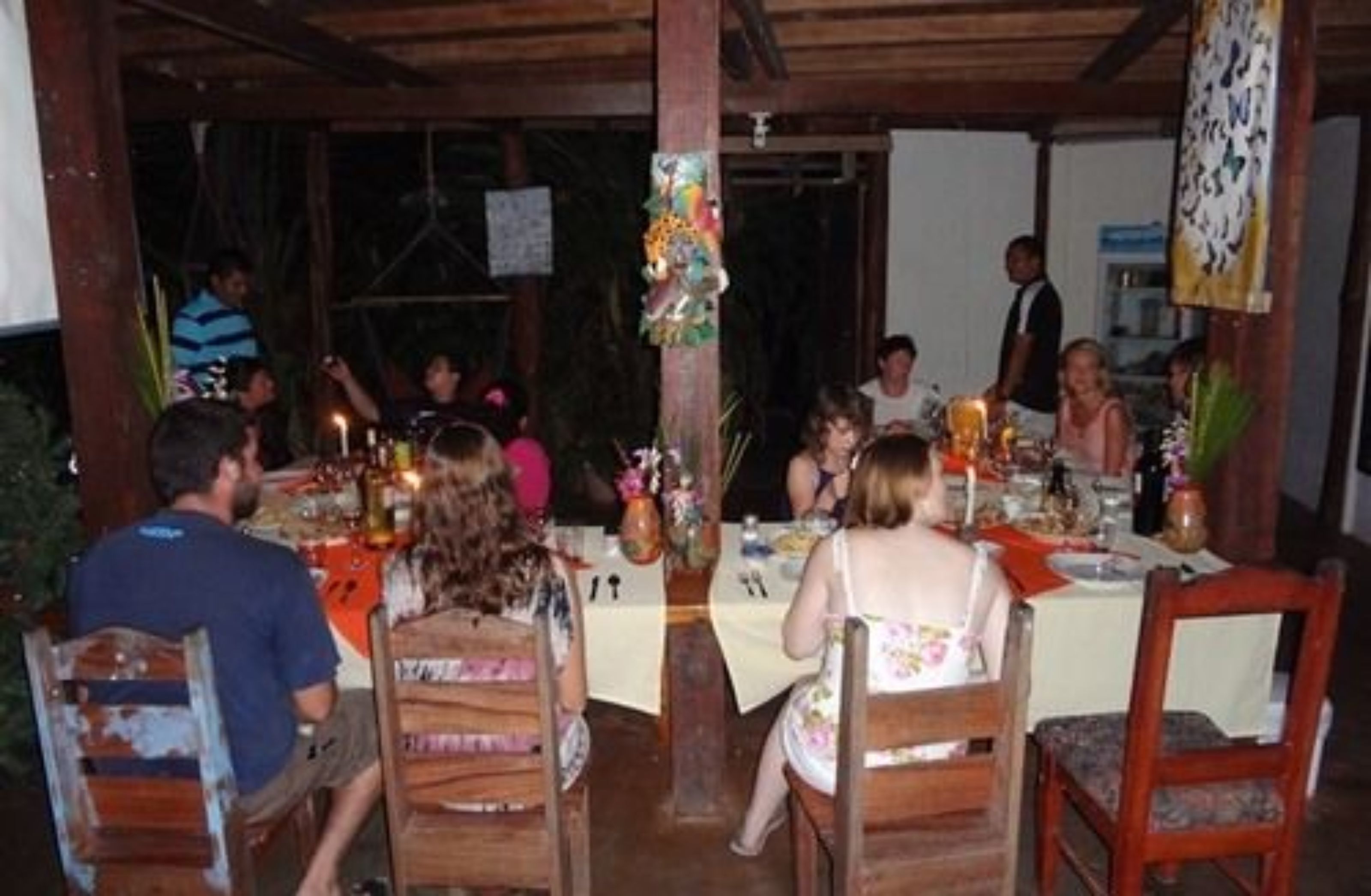 A dining area with wooden tables and chairs, decorated with flowers and candles.