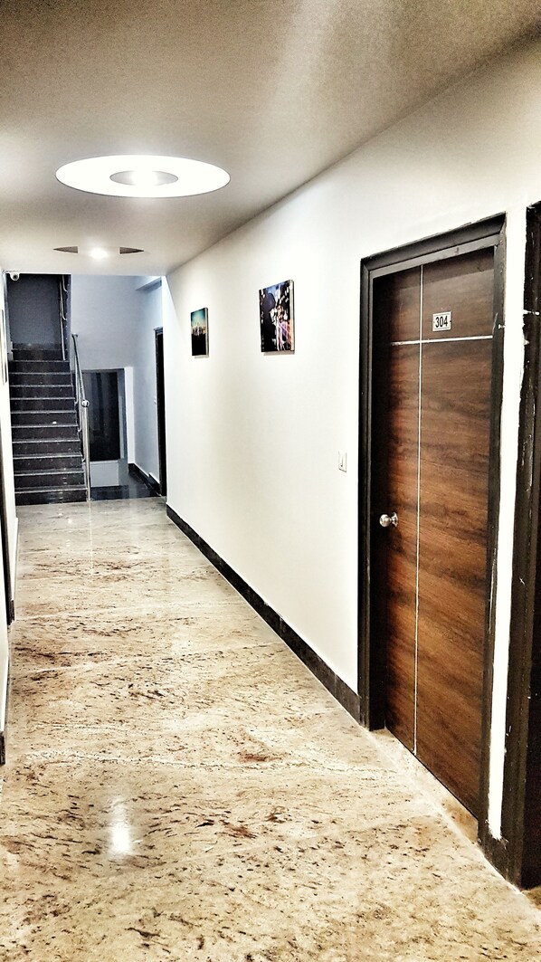 A hallway with a marble floor, a wooden door labeled "304", and a staircase in the background.