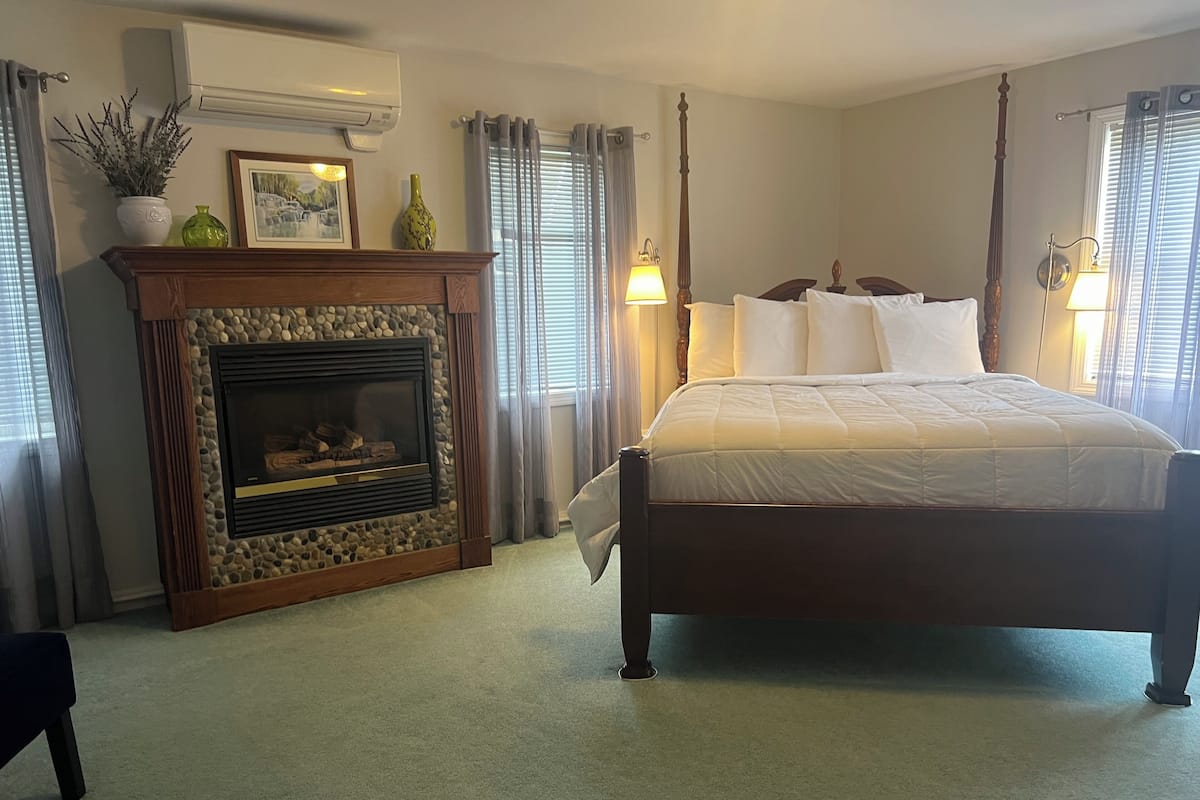 Quarto com uma cama grande, lareira e duas luminárias de cabeceira.