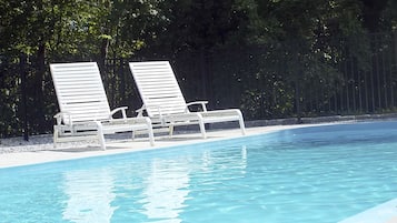 En säsongsöppen utomhuspool och solstolar