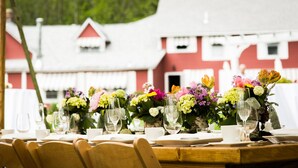 A dining table set for a meal with chairs, a white tablecloth, and a floral centerpiece.