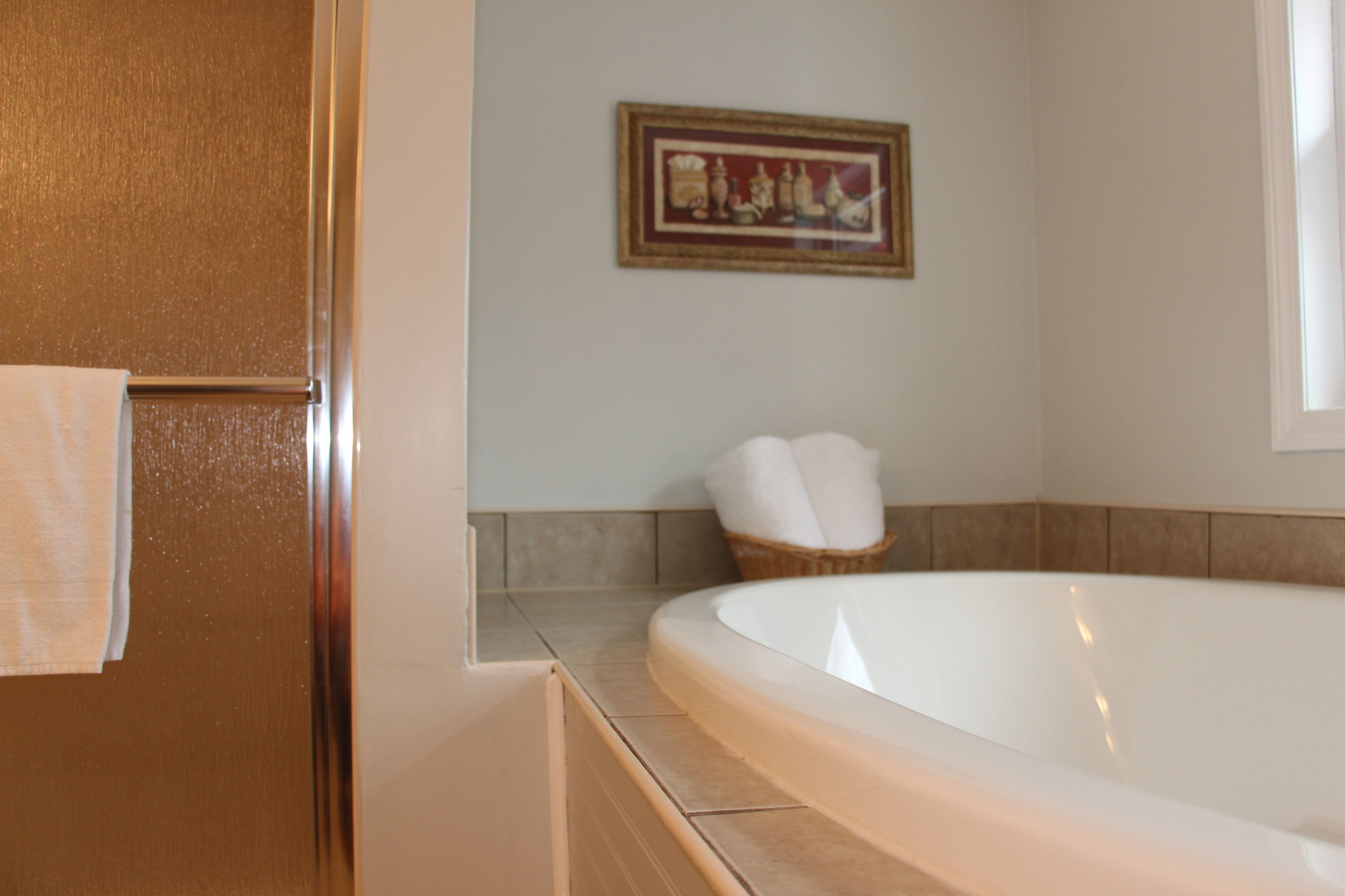A bathroom with a bathtub, a towel rack, and a framed picture on the wall.