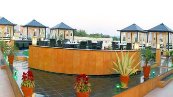 A rooftop terrace with multiple seating areas, potted plants, and a central reception desk.