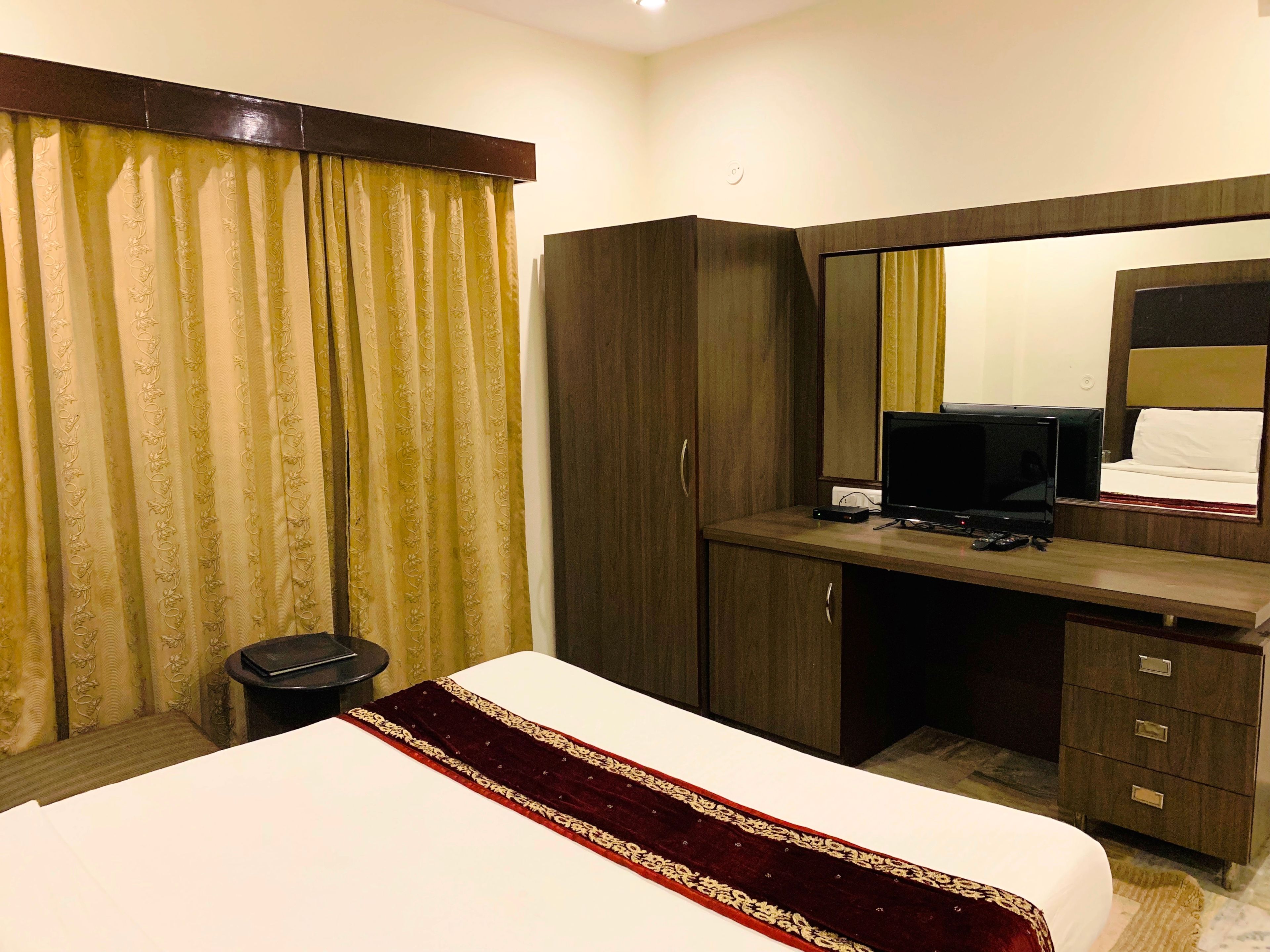 Habitación de hotel con una cama, un escritorio con ordenador, un espejo y un armario.