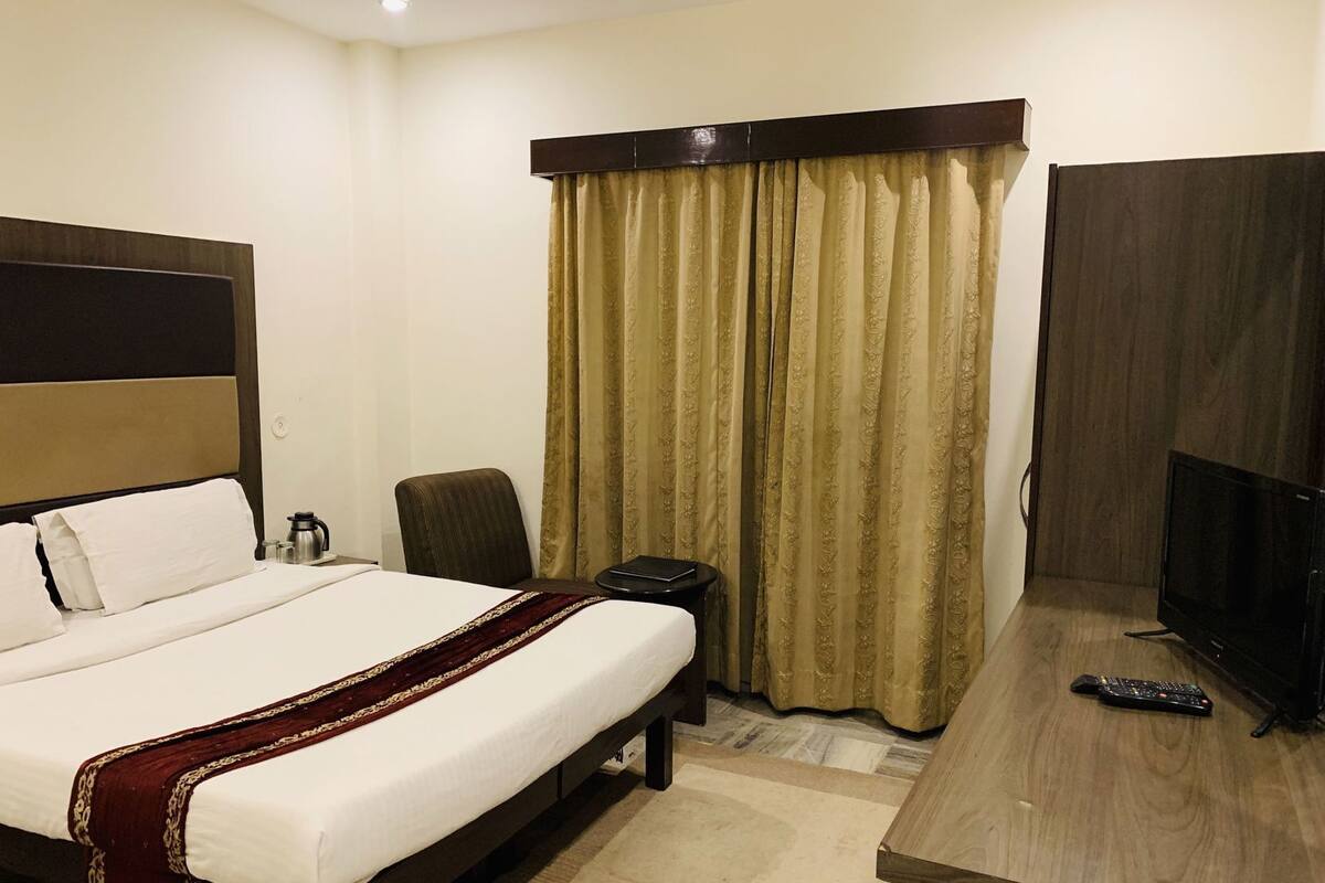 A hotel room with a bed, a desk, a television, and a chair.
