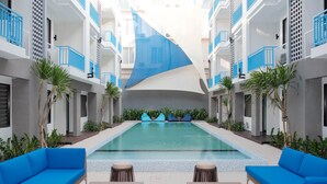 A pool area with blue sofas and lounge chairs, surrounded by white and blue balconies. - Bloo Bali Hotel (Legian)