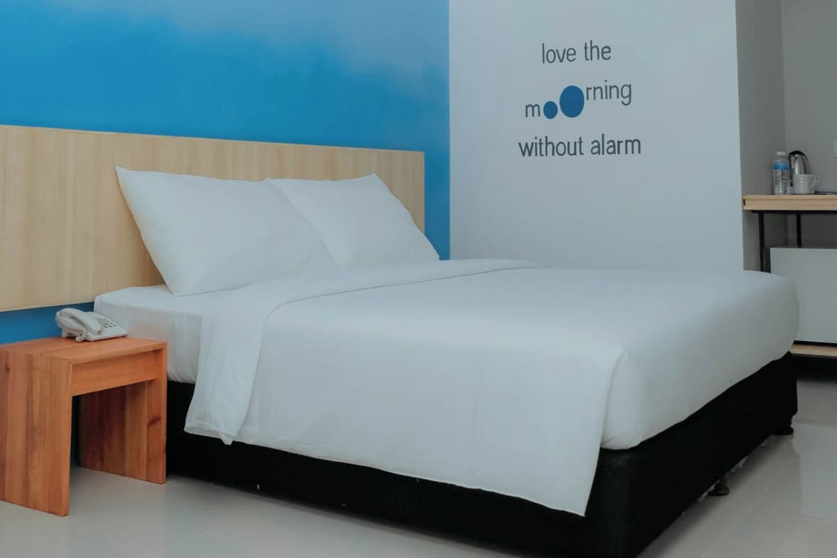 Una habitación de hotel moderna con una cama, una mesita de noche y una pared con una cita motivacional.