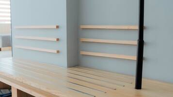 A minimalist room with a wooden bench, a black pole, and a light blue wall.