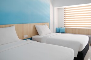 Habitación de hotel con dos camas, cabecero de madera, ventana con persianas y una almohada azul en una cama.
