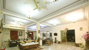 A spacious living room with a marble floor, a sofa set, and a ceiling fan. - Satyam Palace Resort (Pushkar)