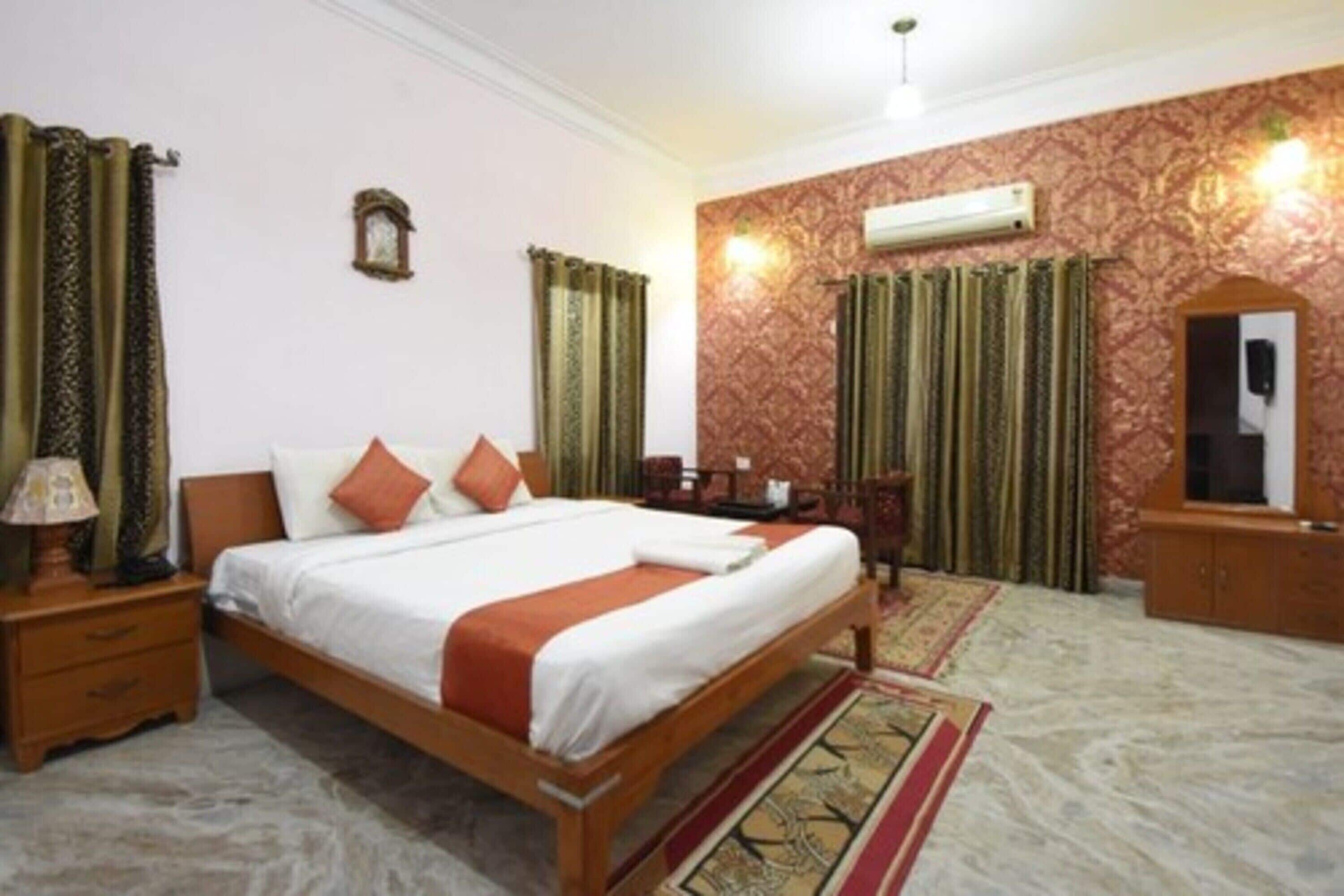 A hotel room with a wooden bed, a nightstand, a dresser, and a mirror.