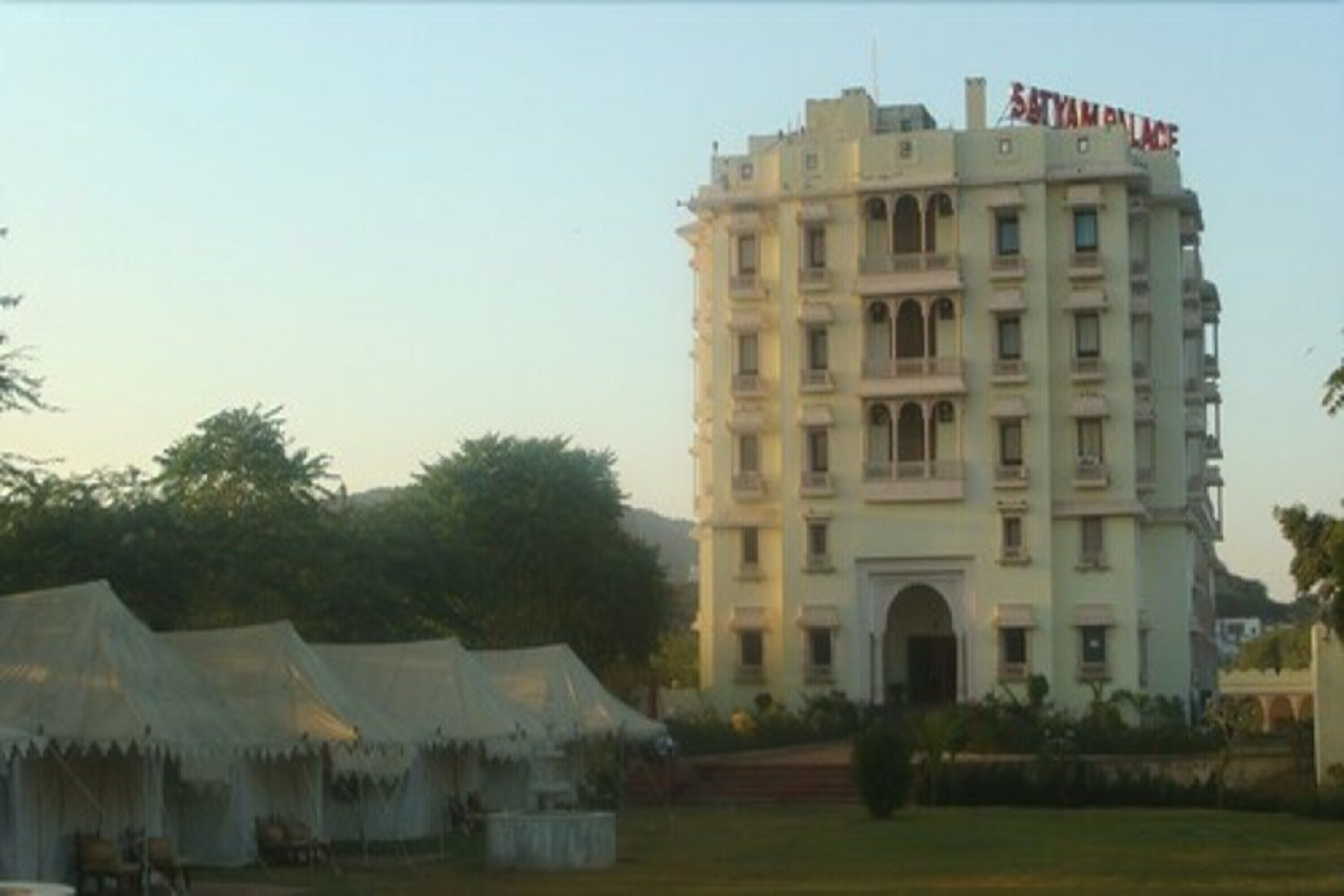 A multi-story building with balconies and a sign reading "Satyam Palace".