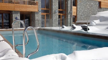 Una piscina al aire libre, sombrillas, sillones reclinables de piscina