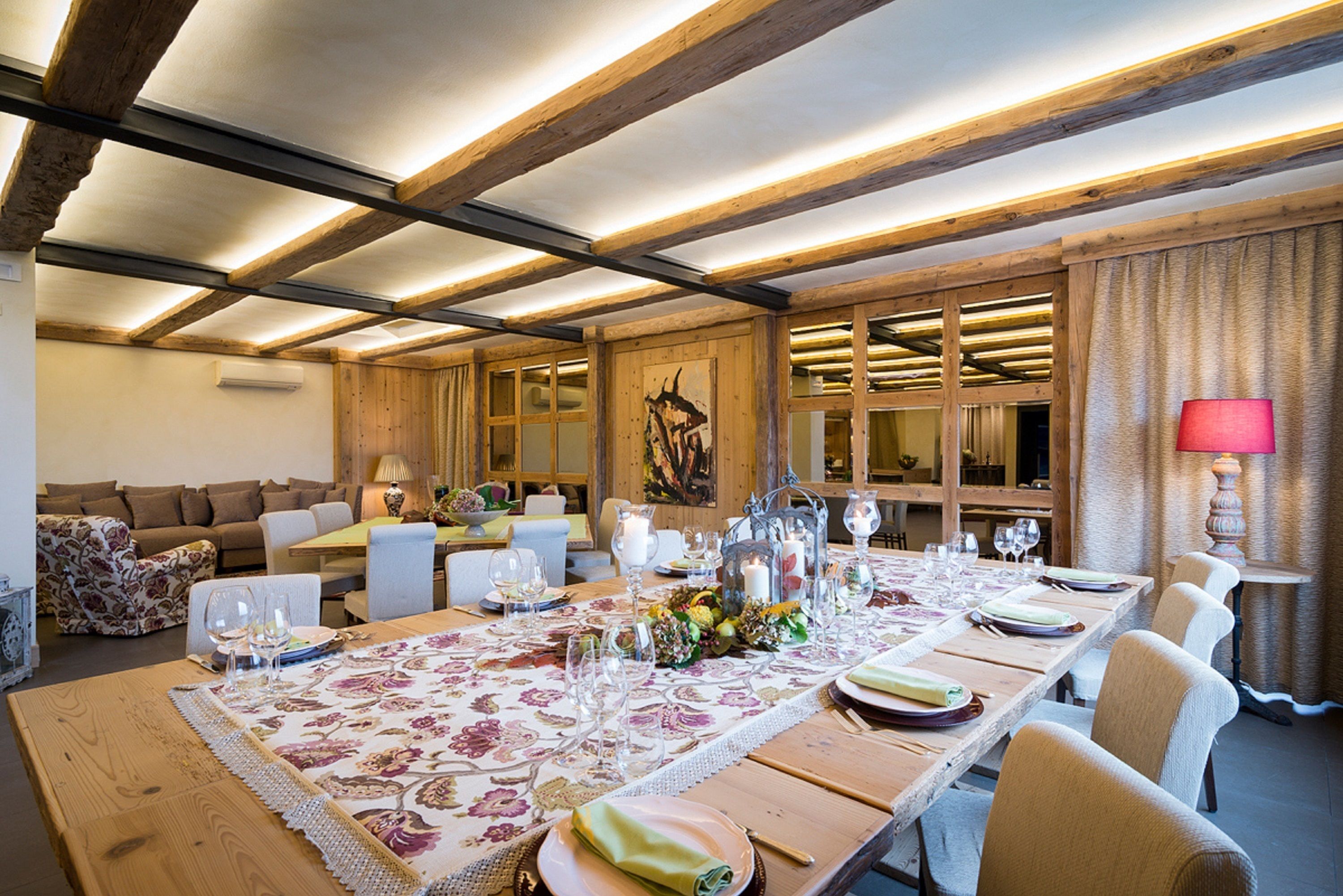 A dining area with a long wooden table set for a meal, surrounded by chairs.