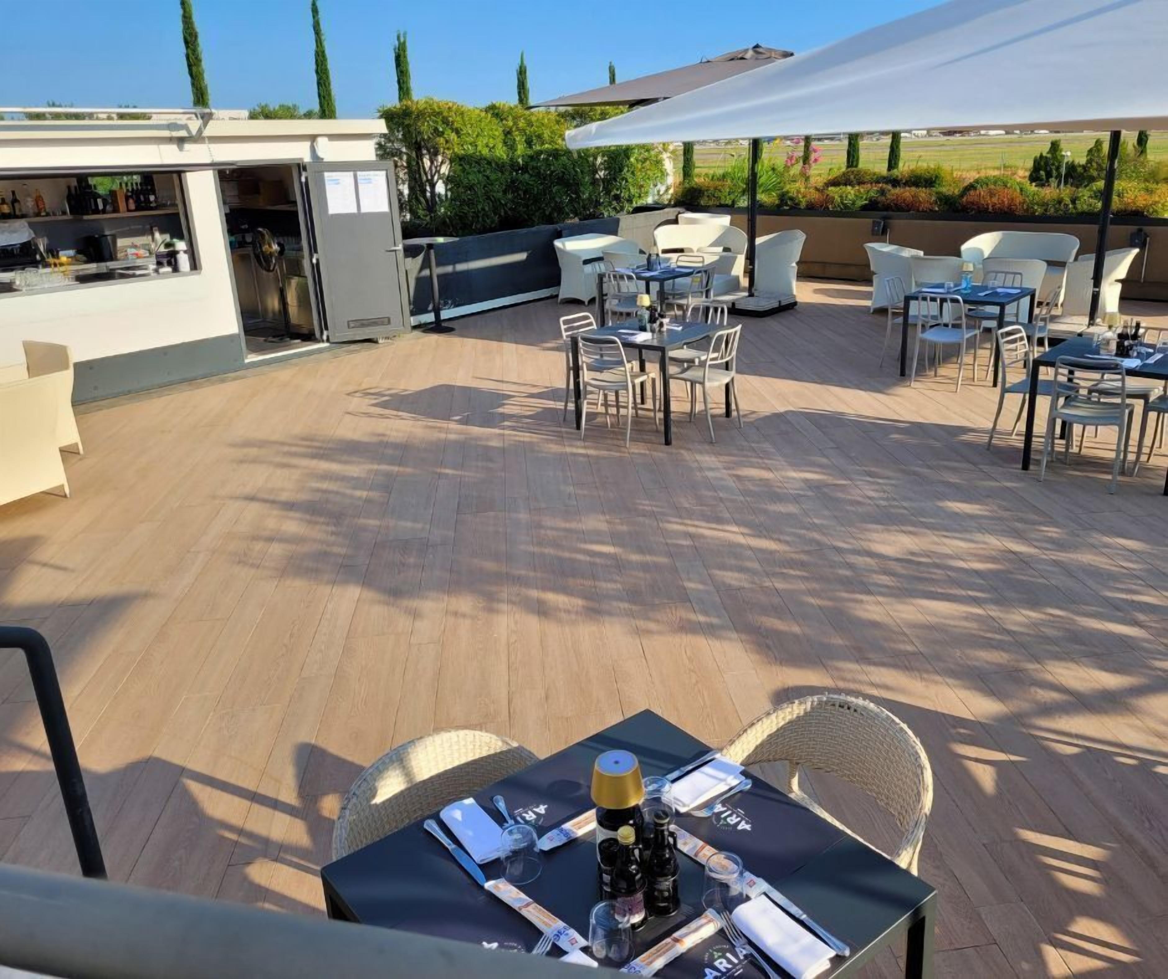 Eine Terrasse im Freien mit Holzboden, weißen Möbeln und einem Essplatz.